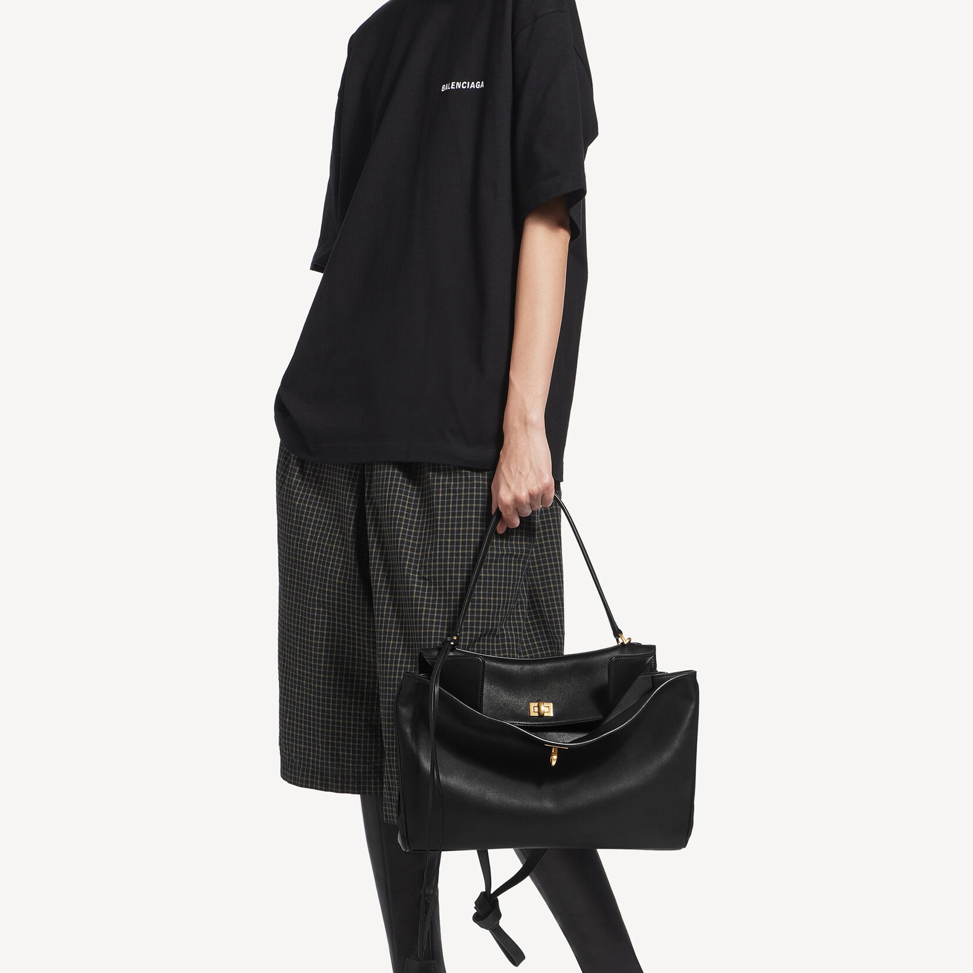 model holding a Black Rodeo inspired leather tote with gold hardware featuring a relaxed rectangular silhouette.