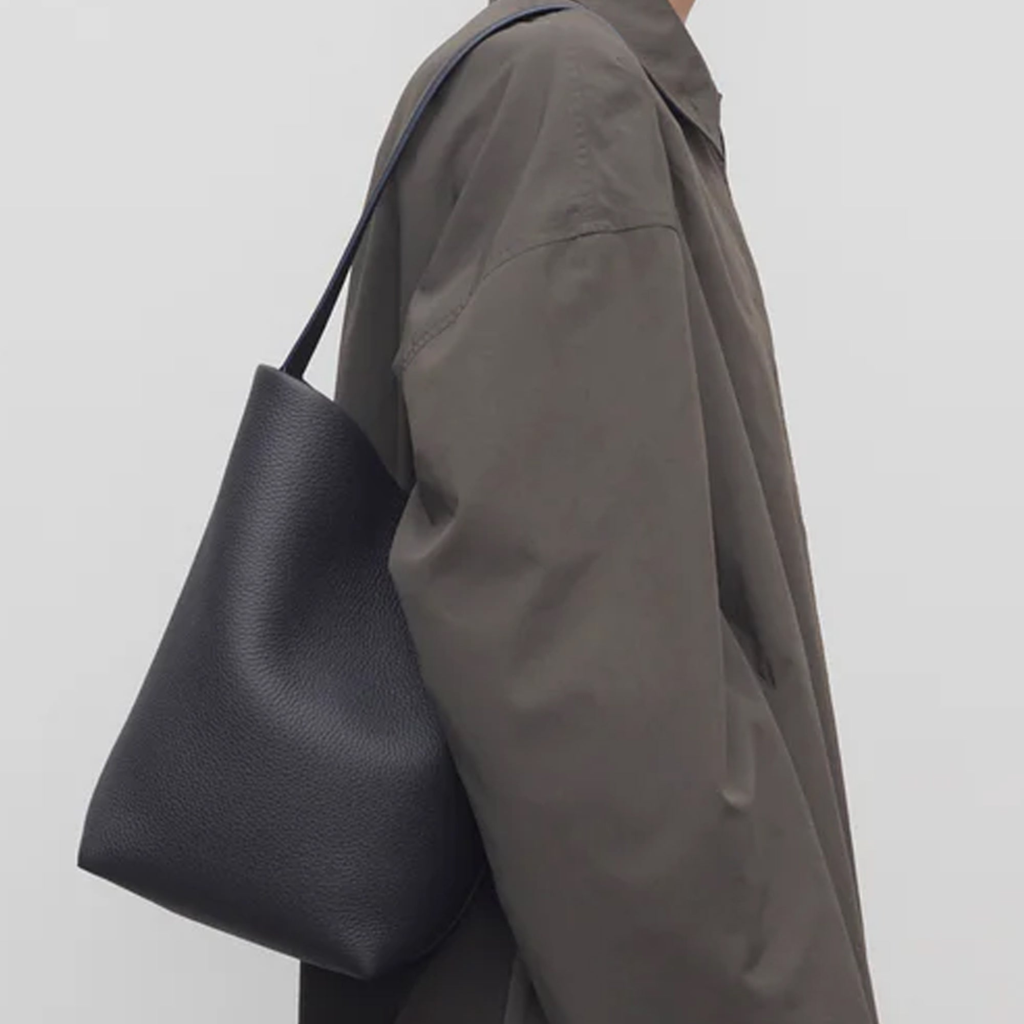 model with the natural grain and soft drape on a Park Tote inspired medium leather bag in black