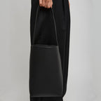 Vertical soft leather tote in black — carried by model