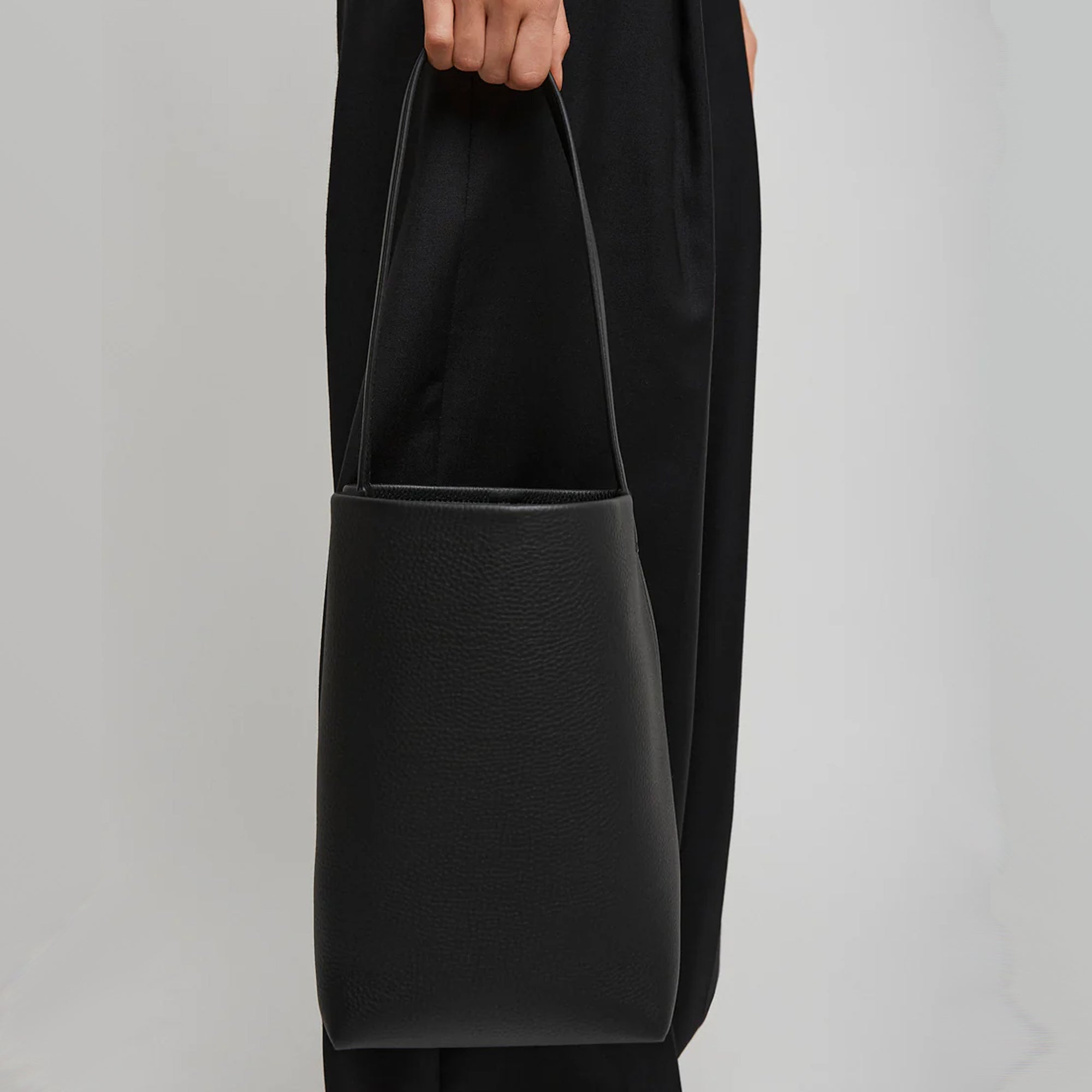 model with the natural grain and soft drape on a Park Tote inspired medium leather bag in black