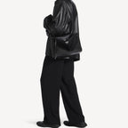 model wearing black slouchy medium tote bag with polished silver hardware and a relaxed rectangular shape.