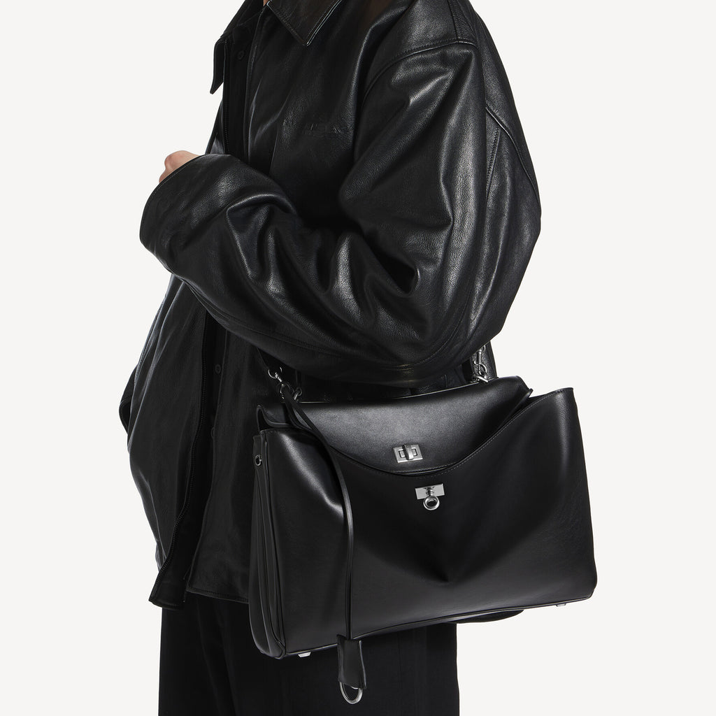 chic model wearing black slouchy medium tote bag with polished silver hardware and a relaxed rectangular shape.