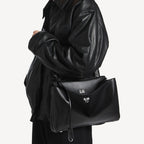 chic model wearing black slouchy medium tote bag with polished silver hardware and a relaxed rectangular shape.