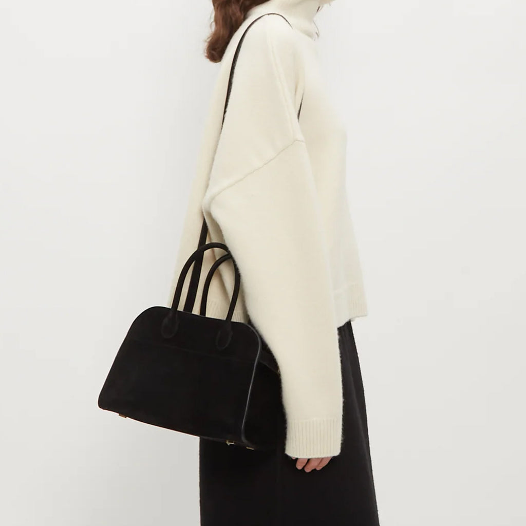 model with Margaux 10 style suede tote bag in black with belted side details.