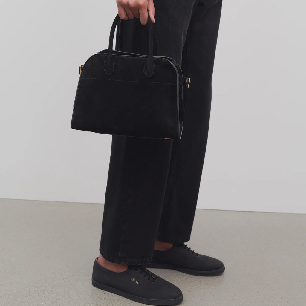 model with Margaux 10 style suede tote bag in black with belted side details.