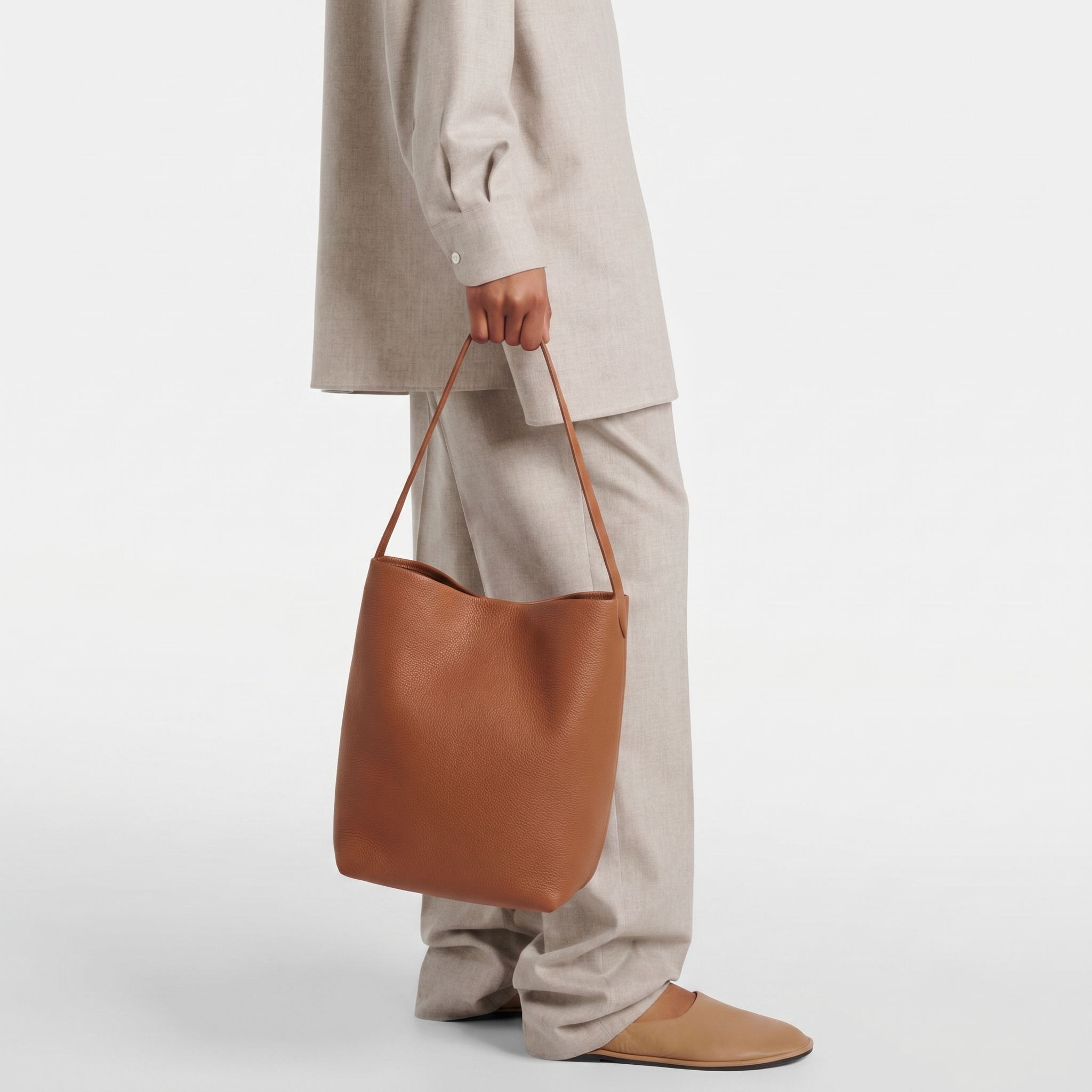 Model holding brown N/S Park style medium vertical tote in genuine leather, showcasing its clean rectangular silhouette.