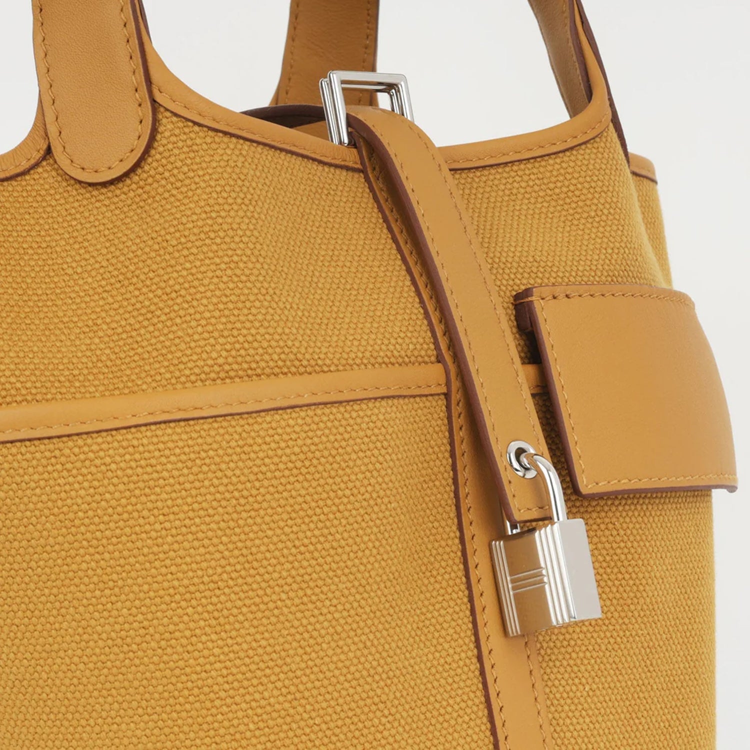 Sesame Beige bucket bag with canvas-style body, vegan leather trim, top-handle, lock strap, and utility side pockets