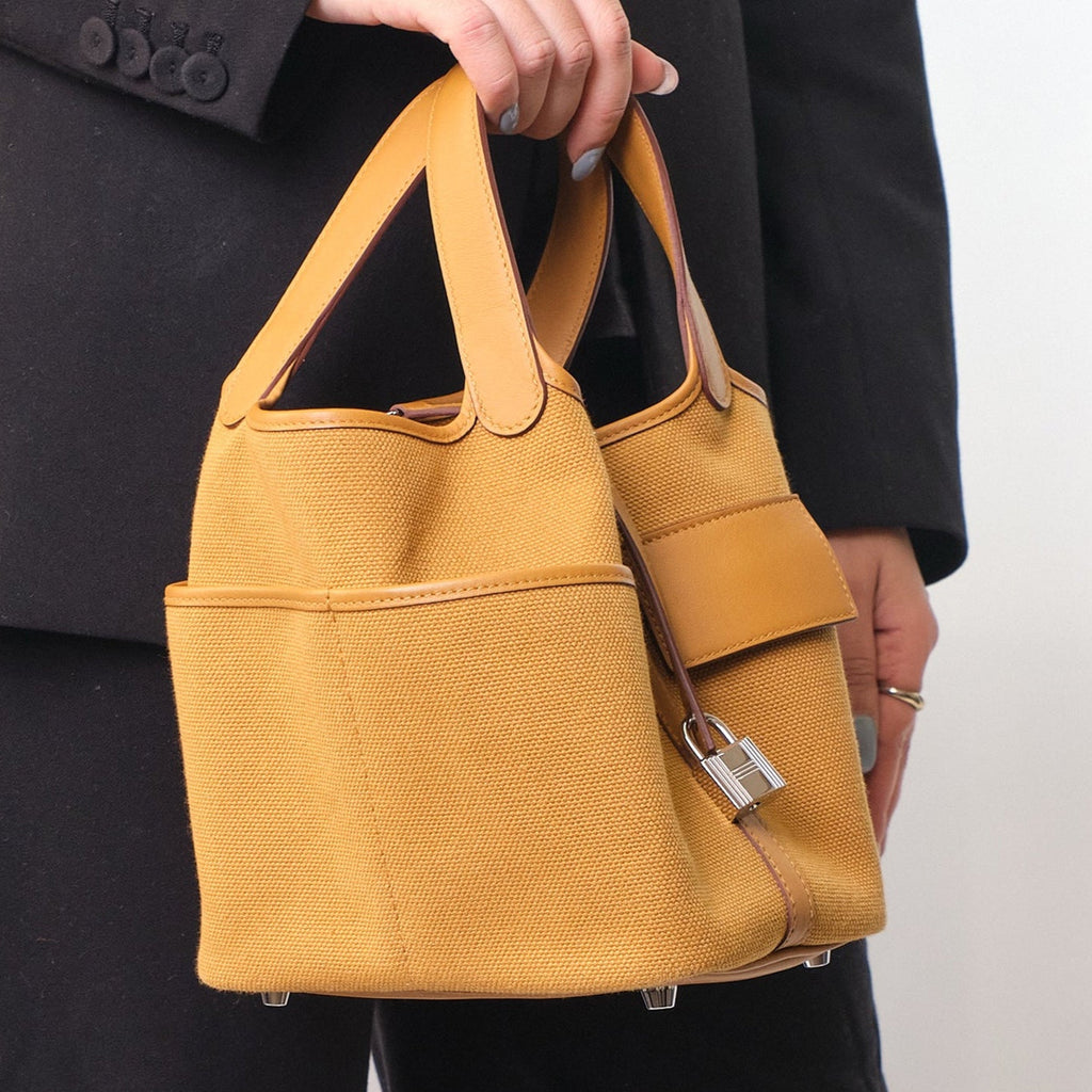 Sesame Beige bucket bag with canvas-style body, vegan leather trim, top-handle, lock strap, and utility side pockets