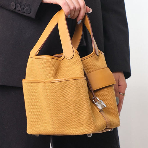 Sesame Beige bucket bag with canvas-style body, vegan leather trim, top-handle, lock strap, and utility side pockets