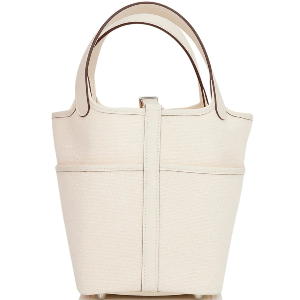 White canvas bucket bag with top handle and structured shape with silver lock