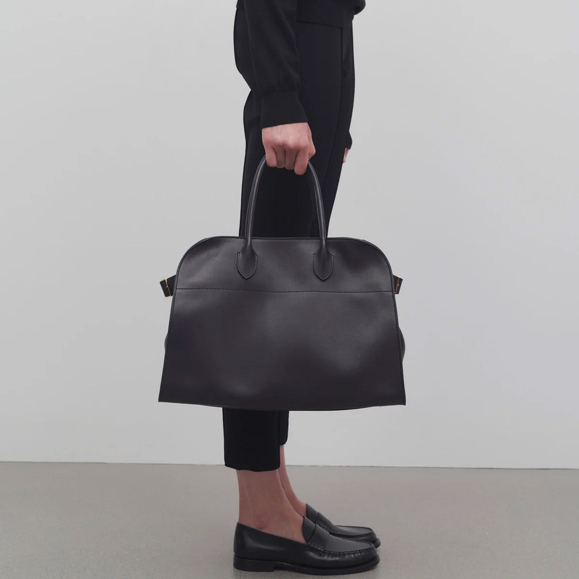 Black leather tote bag with toggle closure and side tabs