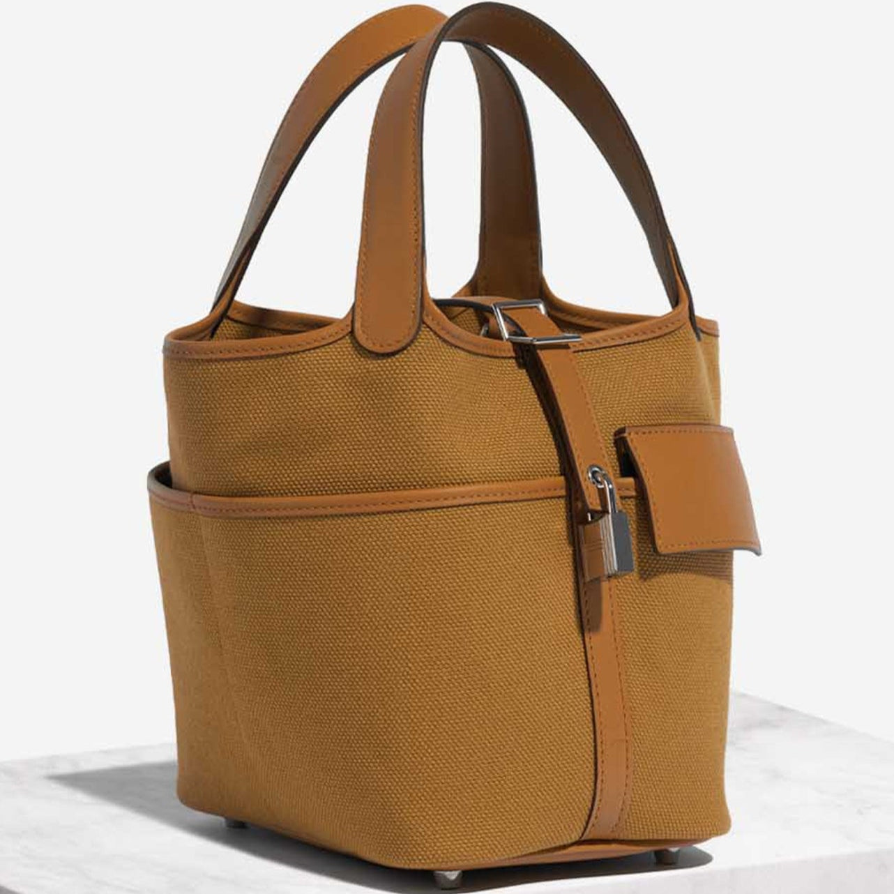 Sesame Beige bucket bag with canvas-style body, vegan leather trim, top-handle, lock strap, and utility side pockets