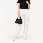 Weekday Tote Mini 23 cm open-top tote in black carried by the top handles with a black tee and white straight-leg jeans, model shot showing the 23 cm size on the body