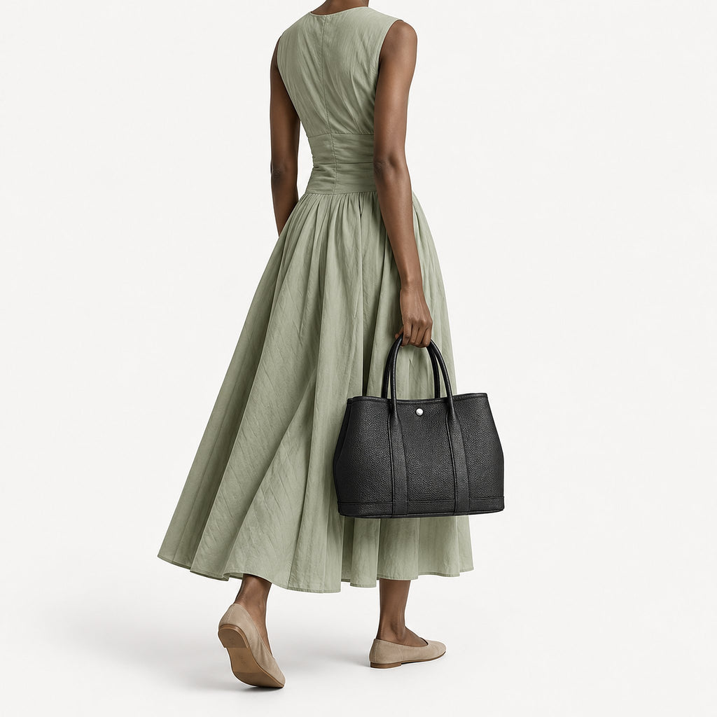 Weekday Tote Medium 30 cm open-top tote in black carried by the top handles with a sage green midi dress, model shot showing the 30 cm size on the body