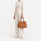 Weekday Tote Medium 30 cm open-top tote in brown carried by the top handles with an ivory knit and wide-leg trousers, model shot