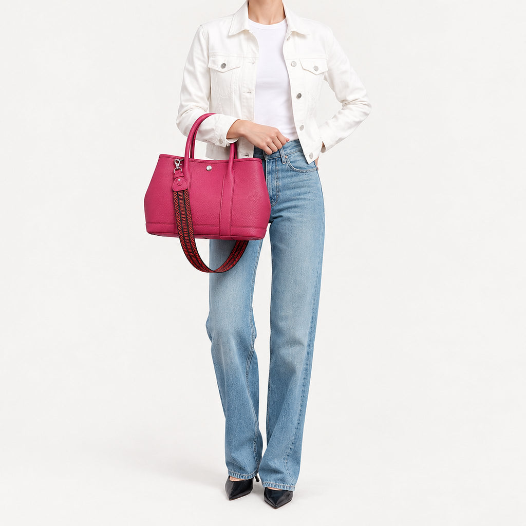 Weekday Tote Medium 30 cm open-top tote in hot pink carried by hand with the included woven strap, styled with a white denim jacket and jeans, model shot