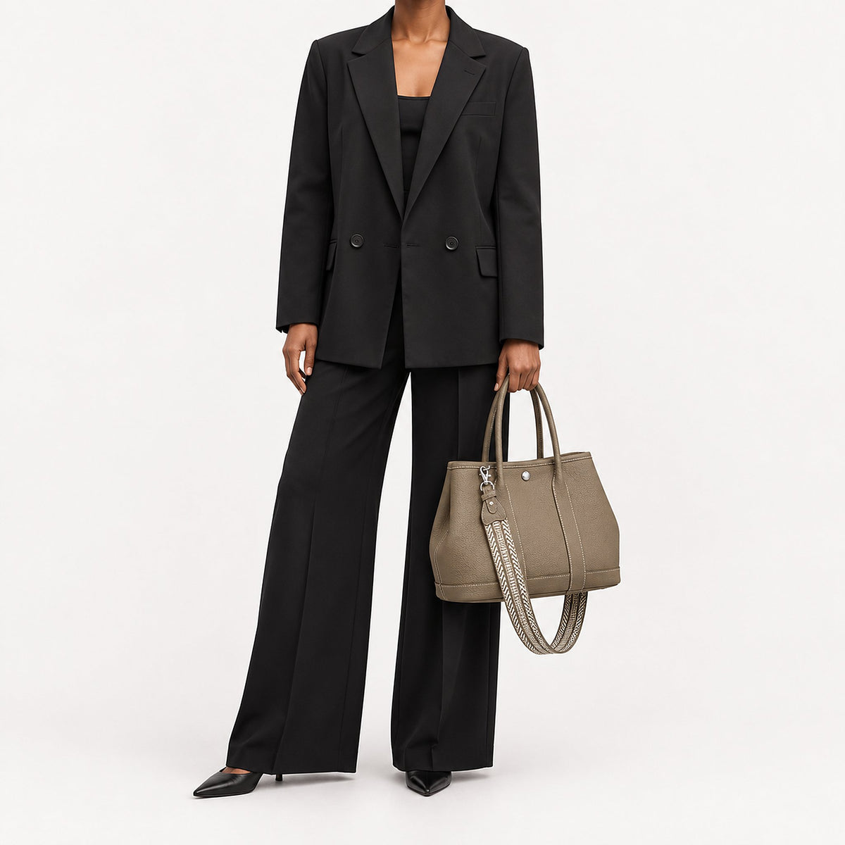Weekday Tote Medium 30 cm open-top tote in khaki carried by hand with the included woven shoulder strap attached, worn with a black trouser suit, model shot